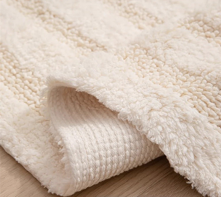 Close-up of the handmade cotton tassel runner rug, showing the textured pile on the top surface and the woven backing on the underside as it is slightly folded.