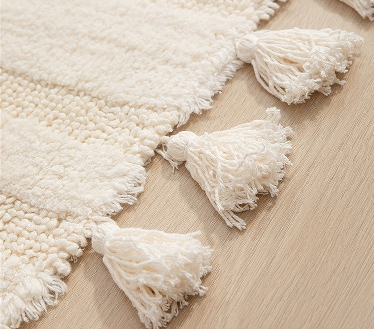 Close-up shot of the handmade cotton tassel details and textured weave of the runner rug in off-white.
