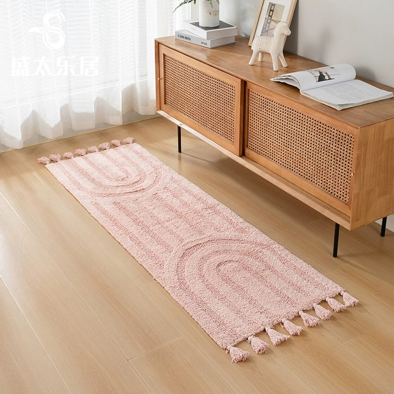 Minimalist rainbow handmade cotton tassel runner rug in blush pink color, styled in a minimalist home decor setting.