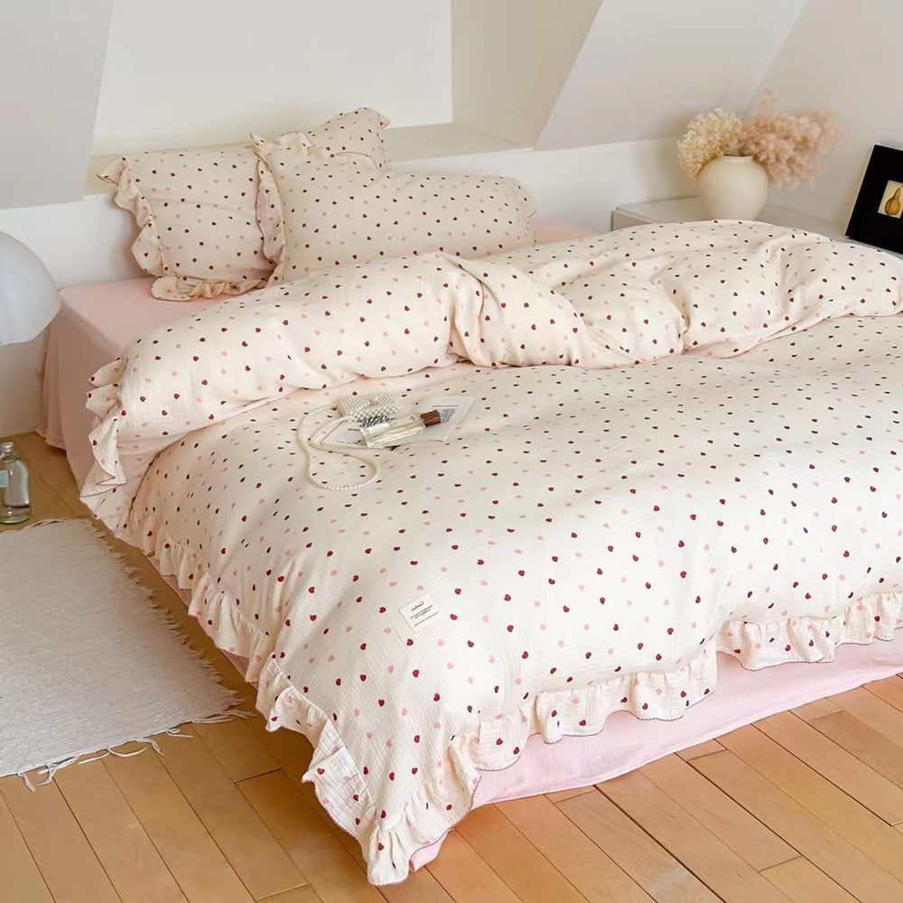 Romantic bedroom scene with a pink heart ruffled duvet cover set styled with a book and perfume bottle