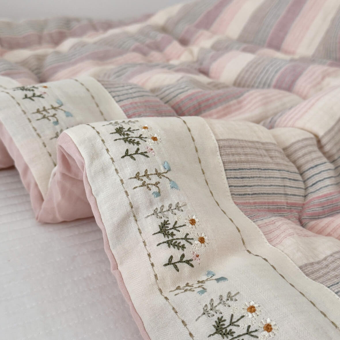 Close-up of a quilt with floral embroidery on a light background
