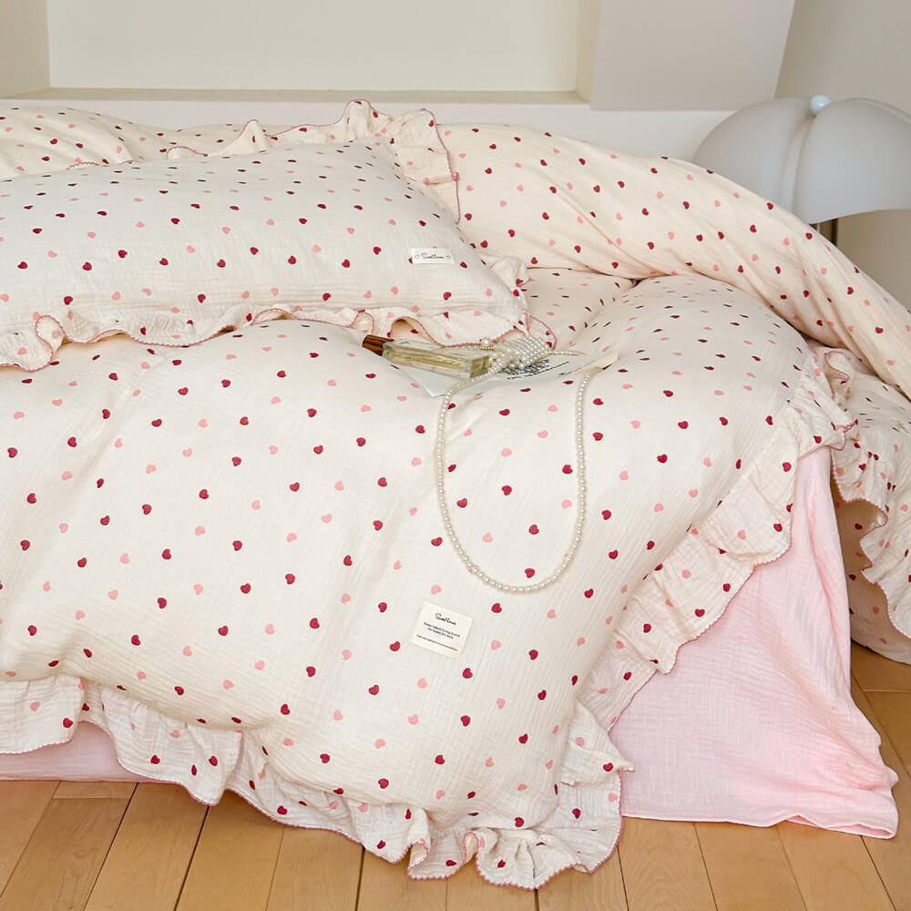 Close-up of a pink heart duvet cover set showing ruffled pillows and the soft texture of the cotton muslin fabric