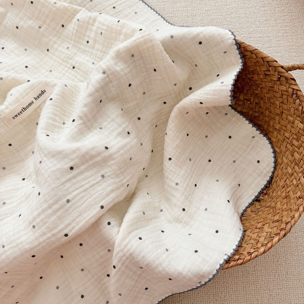 A detailed photo of the Polka Dot muslin blanket, emphasizing its lightweight, breathable fabric and the charming black and gray polka dot pattern.