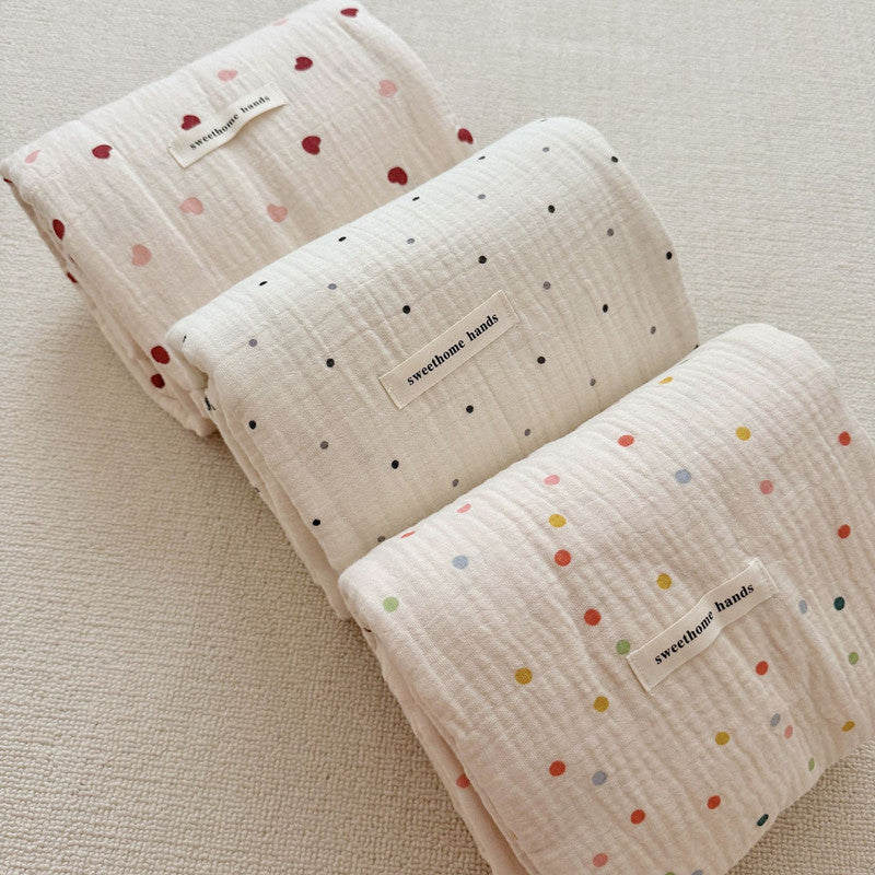 A top-down shot showing three folded muslin blankets with different patterns, with the center one being the black and white Polka Dot design. This image highlights the product's color and pattern variations.