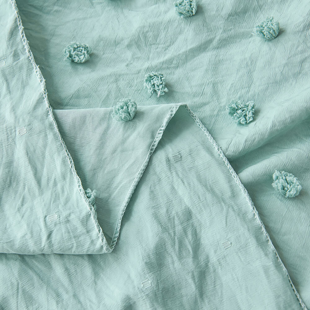 Close-up of sage green polyester canopy fabric with pom pom texture and edge detail