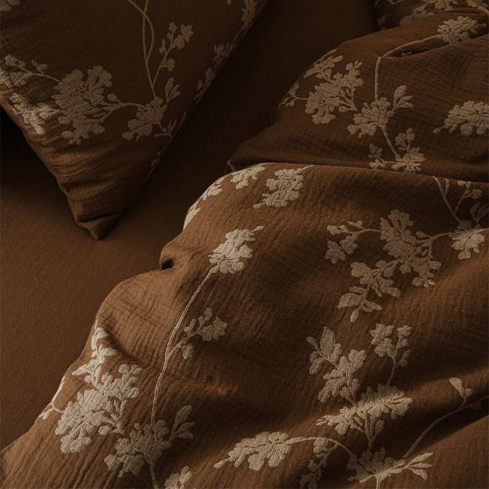 An overhead close-up of the brown floral duvet cover, highlighting the intricate pattern of white flowers and vines.