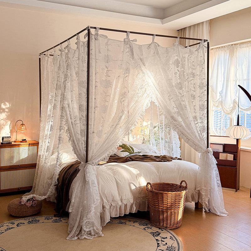 Bedroom with a canopy bed draped in white lace curtains, wooden nightstands, and a wicker basket.
