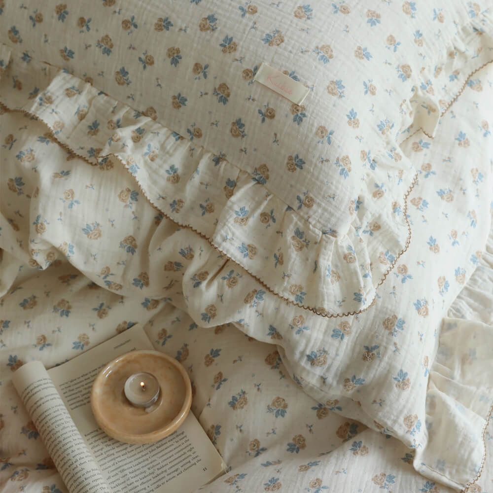 Close-up of blue rosebud duvet cover with gathered ruffles and tan scallop stitching