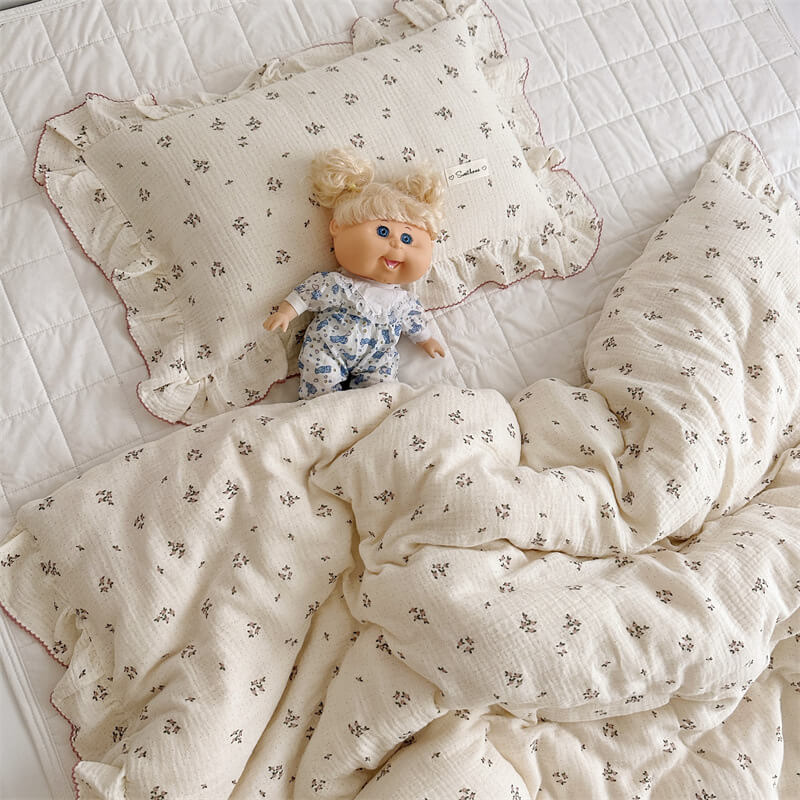 Primrose floral ruffle bedding and pillow set styled with a doll on white quilt