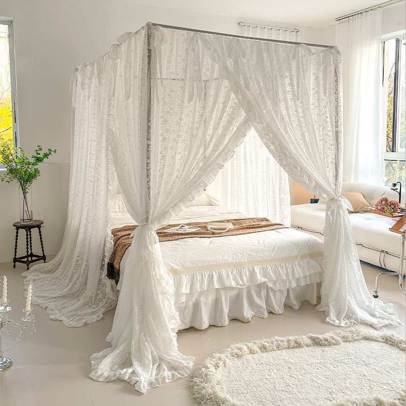 Bedroom with a canopy bed draped in white curtains, surrounded by natural light.