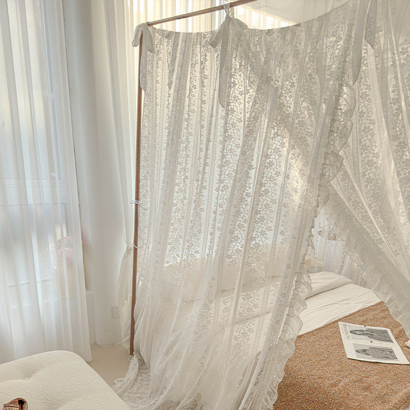 Sheer white curtains draped over a bed in a softly lit room