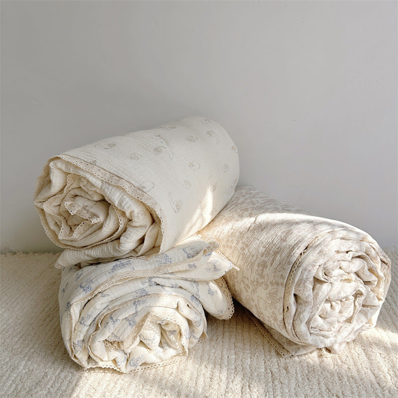 Three animal print comforters in lamb, kitty, and woodland patterns, crafted from breathable cotton muslin with lace trim, layered together