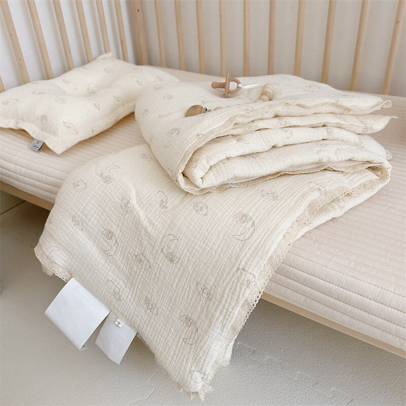 Lamb print comforter and pillow set in breathable cotton muslin, displayed on a light wood toddler bed