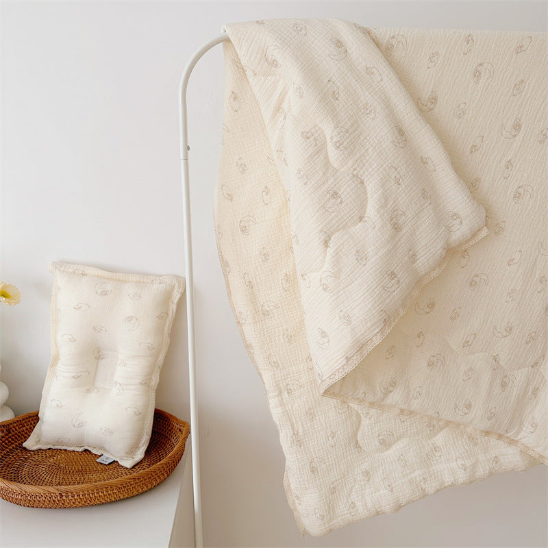 Lamb print comforter and pillow, made from airy cotton muslin with lace trim, hanging and displayed in a bright nursery.