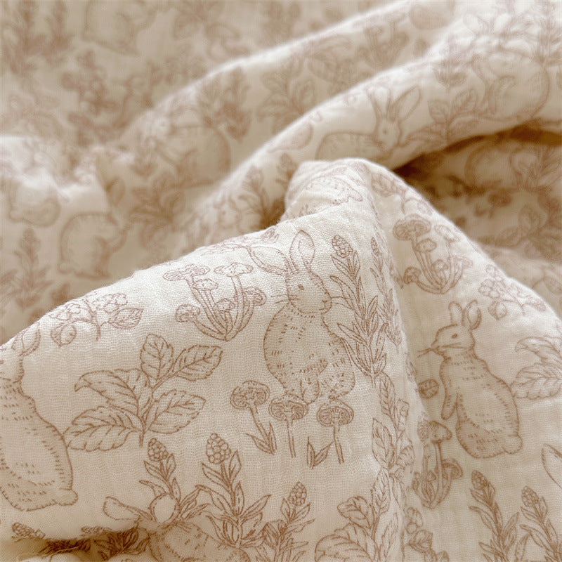 Detailed close-up of the woodland animal print on cotton muslin comforter, showing bunnies, plants, and mushrooms.