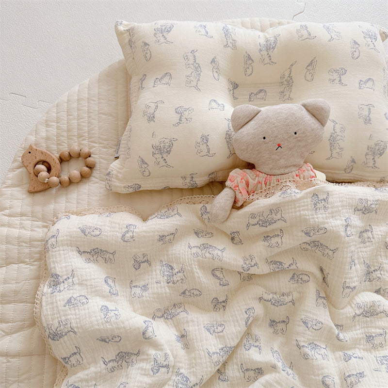 Kitty print comforter and matching pillow in soft cotton muslin, displayed with a plush bear and wooden rattle.