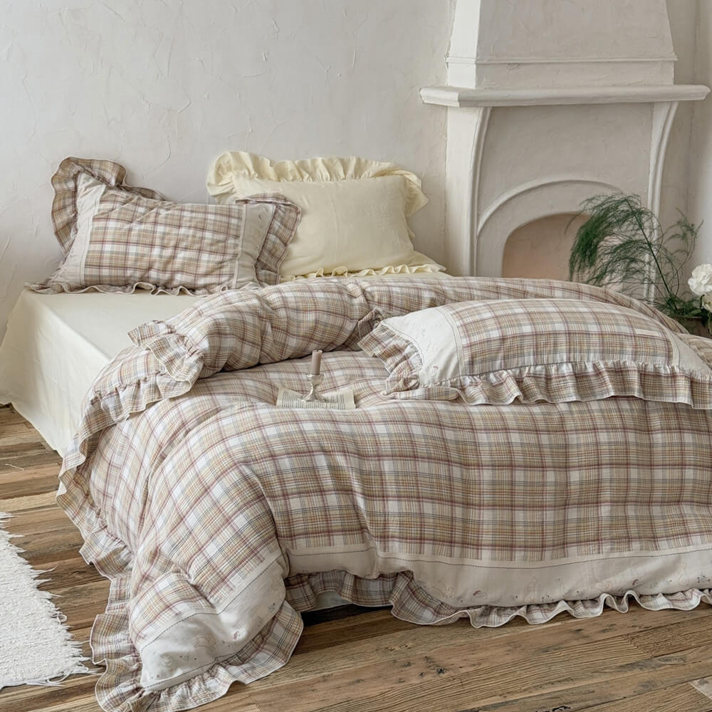 Beige plaid bedding set displayed with matching pillowcases and cream accent pillow in a rustic bedroom