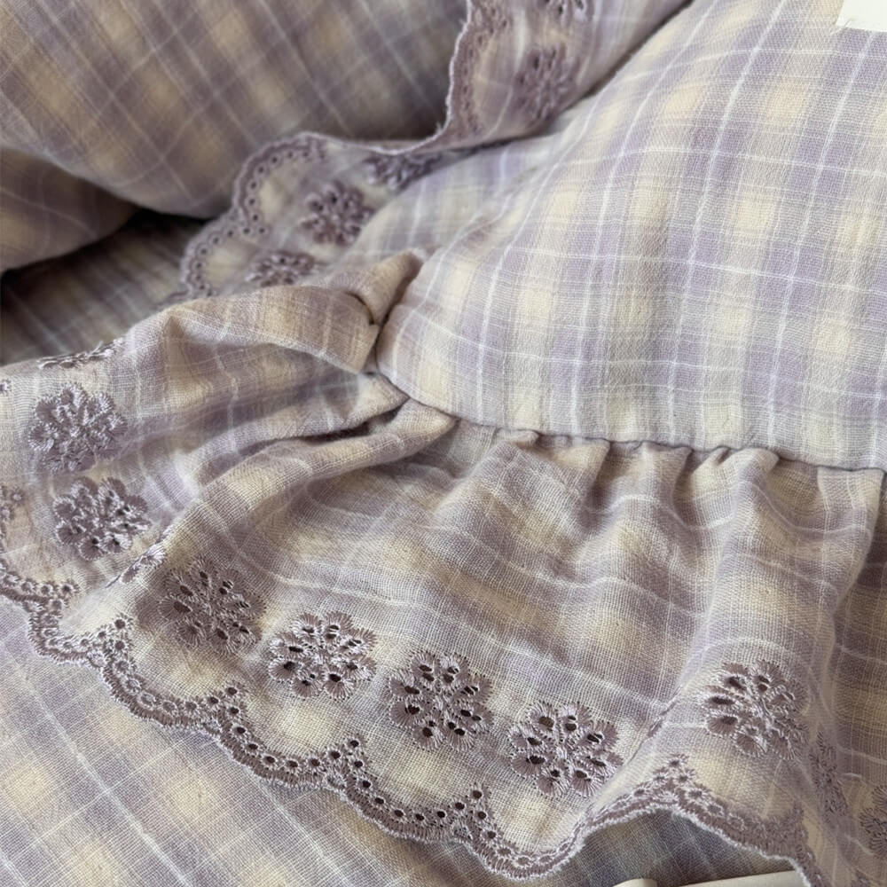 Embroidered floral lace detail on ruffled edge of lavender plaid bedding