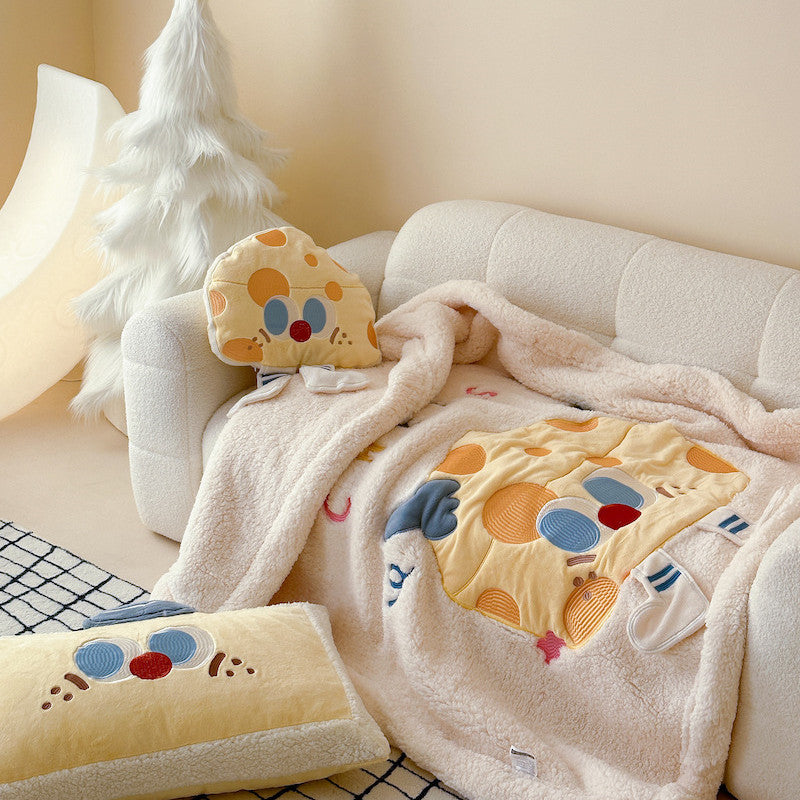 A soft plush sherpa baby blanket with a cheese character design and matching throw pillows on a sofa.