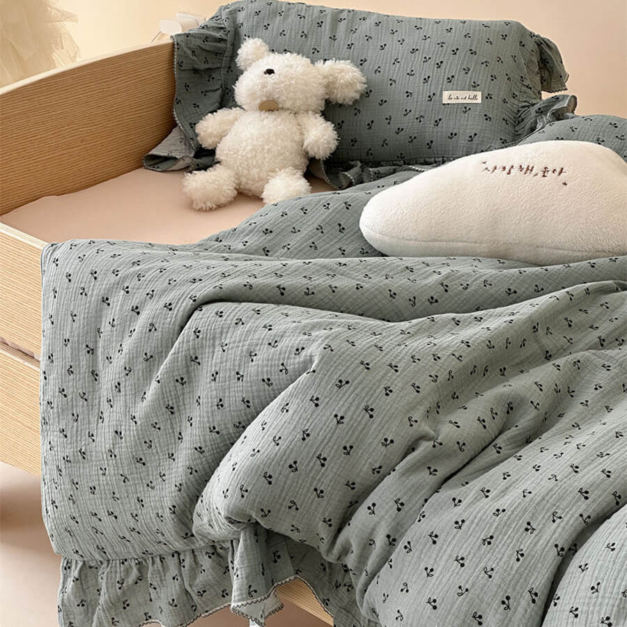 Soft sage floral cotton gauze bedding set for kids, styled with a white teddy bear and a cloud pillow to create a cozy and inviting nursery.