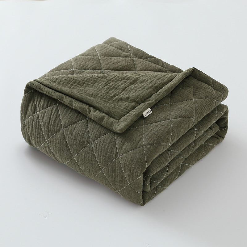 Olive green cotton muslin baby quilt folded neatly with visible soft crinkled surface