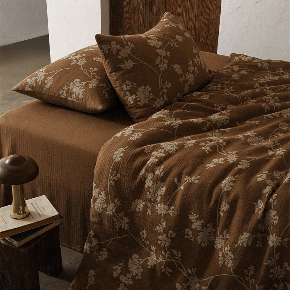 A close-up of a bed with a brown floral cotton gauze duvet cover set, featuring a delicate floral pattern on a rich brown background.