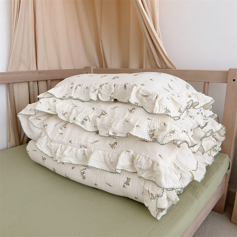 Bunny and leaf print muslin bedding set folded, showing green ruffle trim