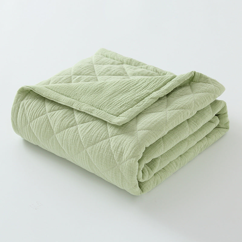 mint green cotton muslin baby quilt folded with soft crinkled fabric and stitched surface