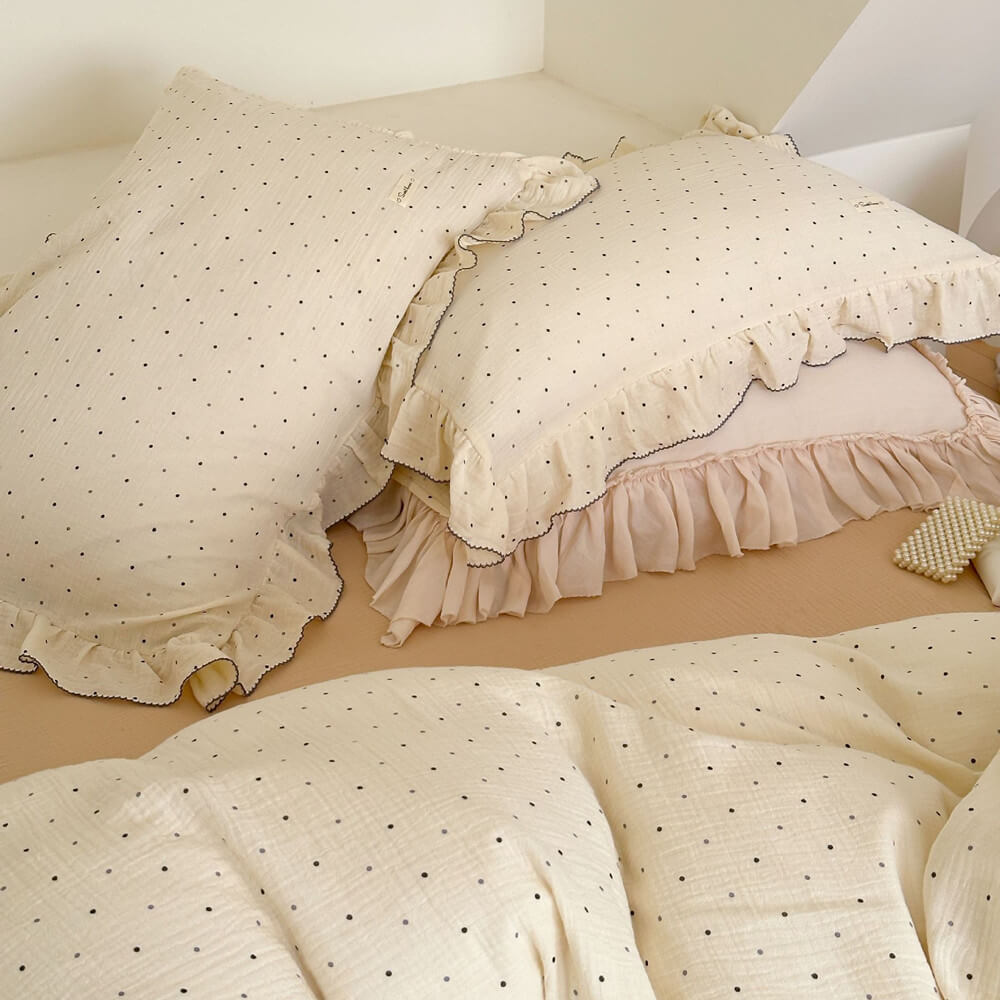Ruffled polka dot pillowcase and duvet cover in white cotton gauze on bed,