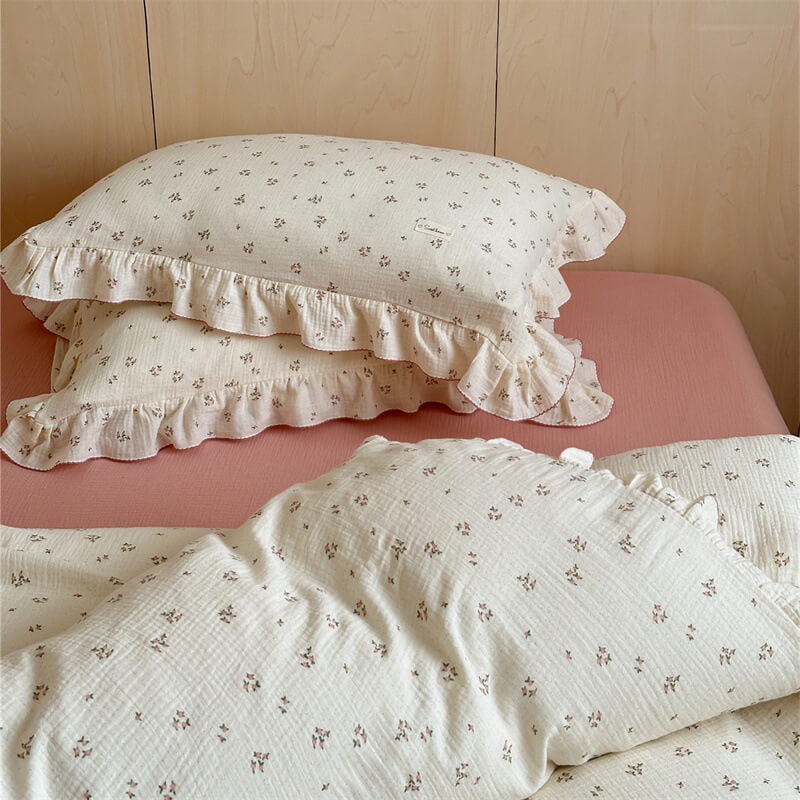 A bed with a small pink floral duvet cover set with matching pillows and brush pink flat sheet