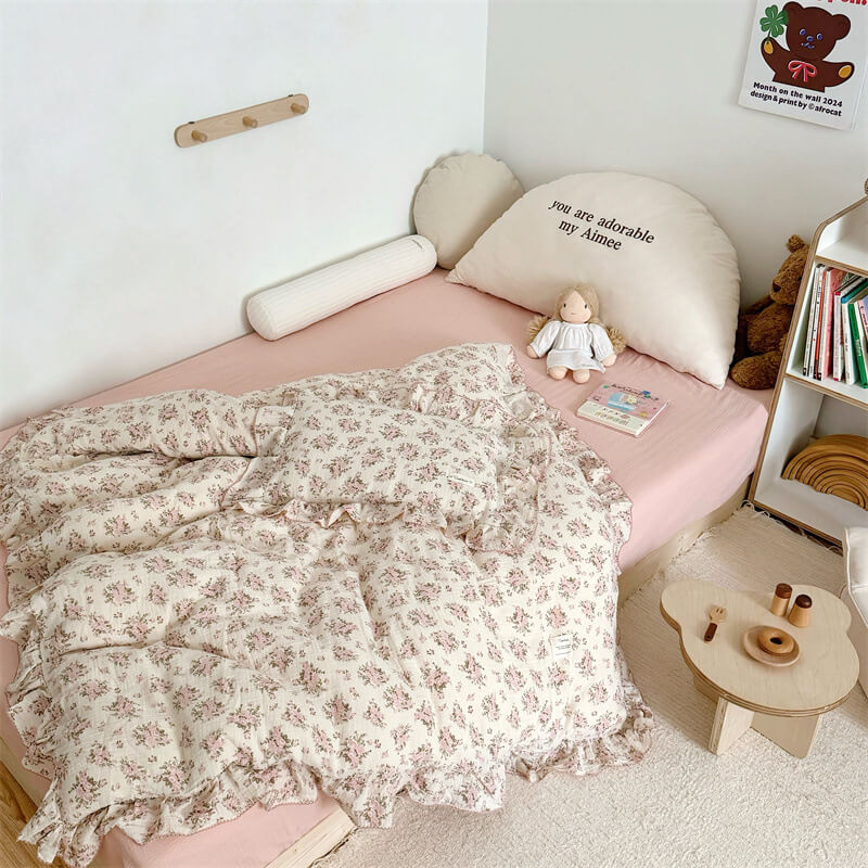 Full view of Cotton Gauze Pink Rose Ruffle Bedding Set with doll on top