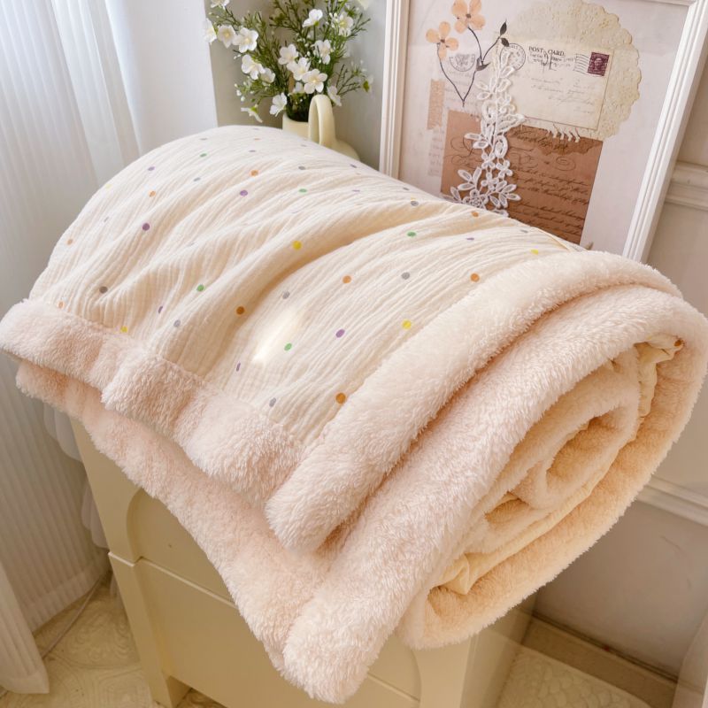 A warm baby blanket for a stroller, with a polka dot pattern and a cozy fleece lining, neatly folded on a cabinet.