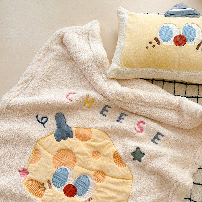 Close-up of a warm sherpa baby blanket, highlighting the embroidered cheese design.