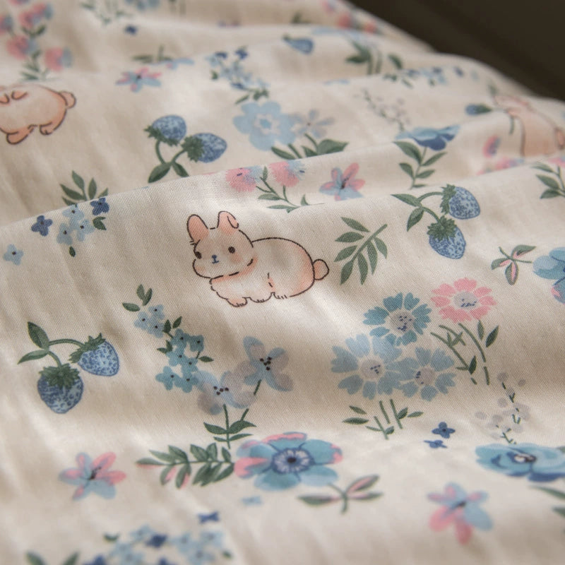 An extreme close-up of the fabric from the bedding set, highlighting the detailed print of a smiling bunny among small blue and pink flowers.