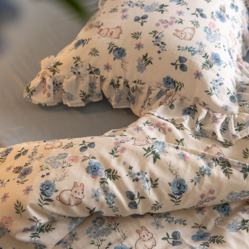 A lifestyle photo of the blue floral bunny bedding set, showing the full duvet cover on a bed in a sunlit room.