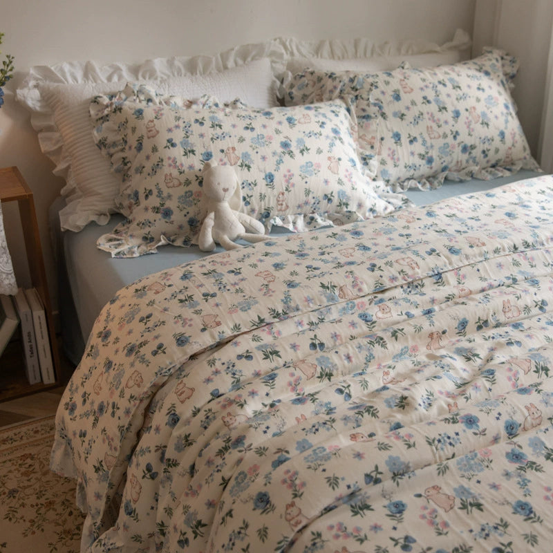A bed styled with a blue floral bunny bedding set, featuring a duvet and pillowcases with a charming print.