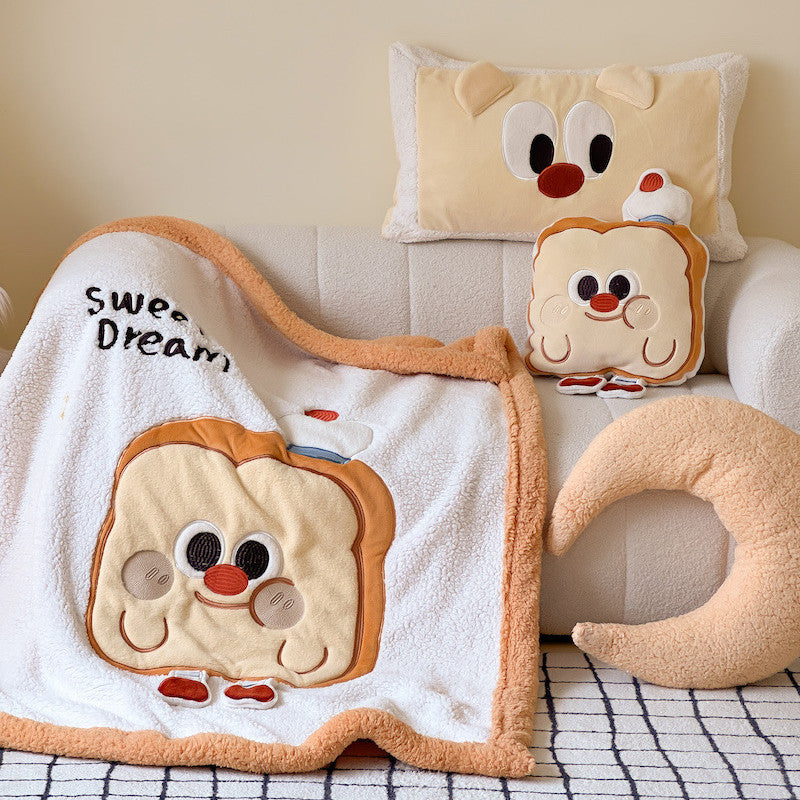 A fluffy plush sherpa baby blanket with a smiling toast character design, arranged on a sofa.