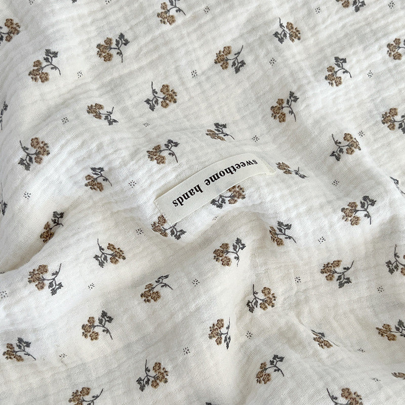Detailed view of the Calendula Floral muslin blanket, focusing on the vintage-style mini-sprig print and the soft texture of the pure cotton fabric.