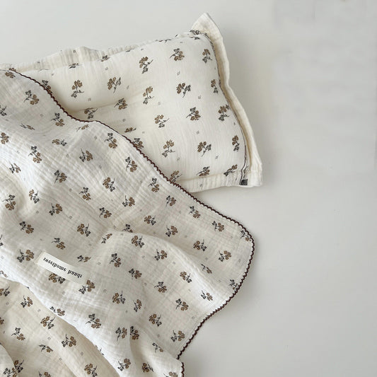 The Muslin Toddler Blanket & Pillow Set in Calendula Floral pattern, featuring a soft blanket and matching pillow laid together, highlighting the complete bedding set.