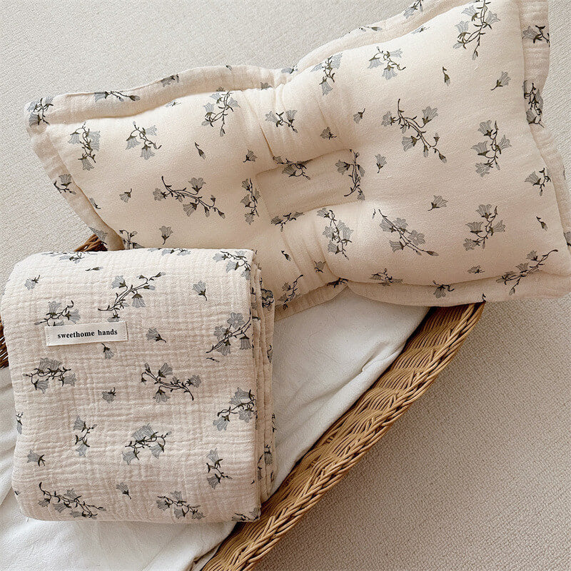 The Hyacinth Floral muslin blanket and pillow set, neatly folded in a woven basket, showcasing a harmonious and peaceful design.