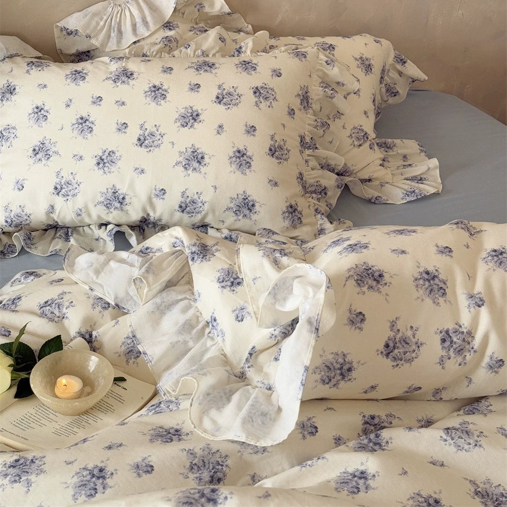 Detail shot of a ruffled pillowcase from the Dusty Blue Floral Bedding set, highlighting the soft cotton muslin fabric and the delicate blue rose pattern.