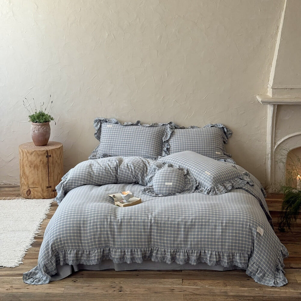 Blue plaid bedding set with wide ruffles and lace, displayed in a soft natural-light bedroom