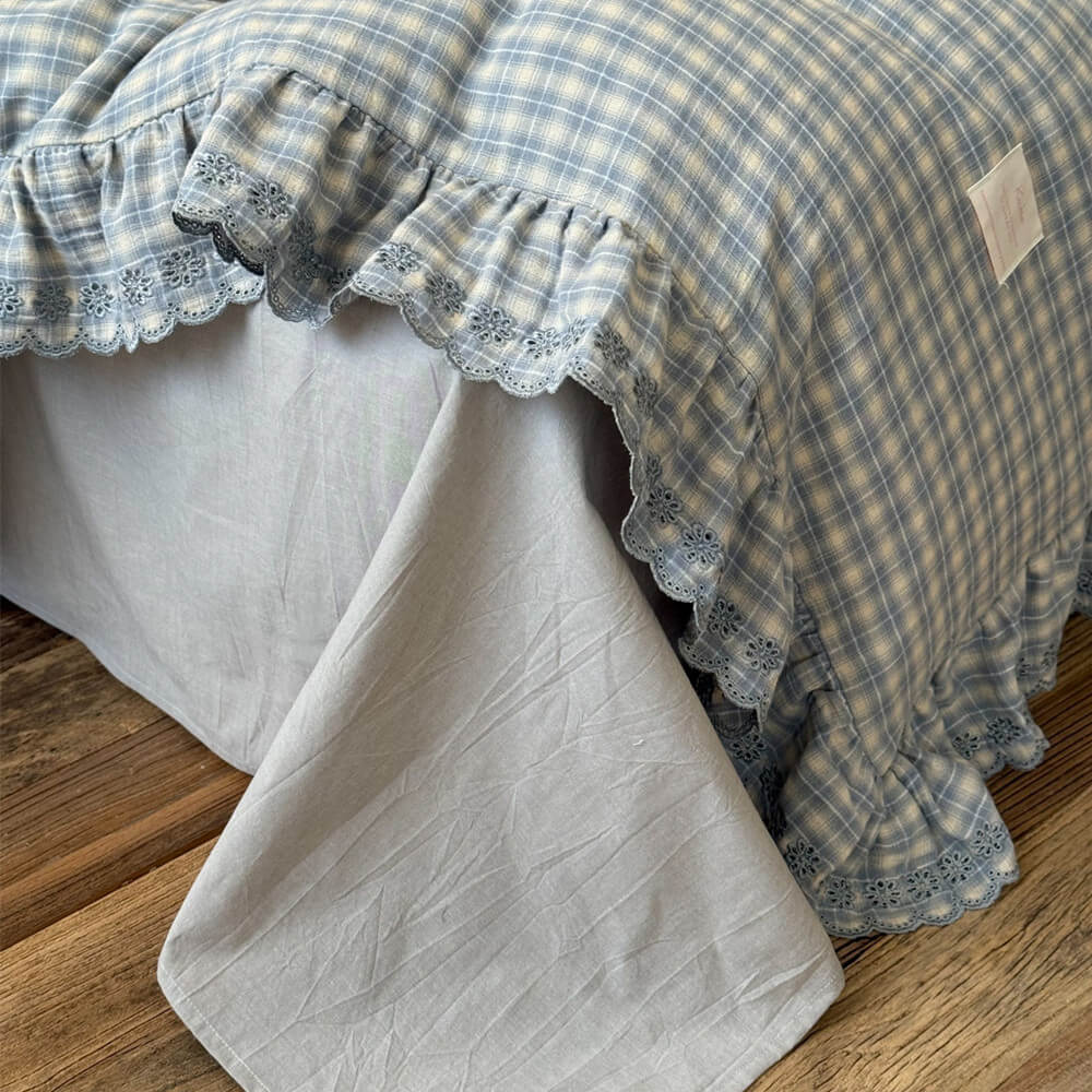 Close-up of lace trim and ruffled edge on blue plaid cotton muslin bedding
