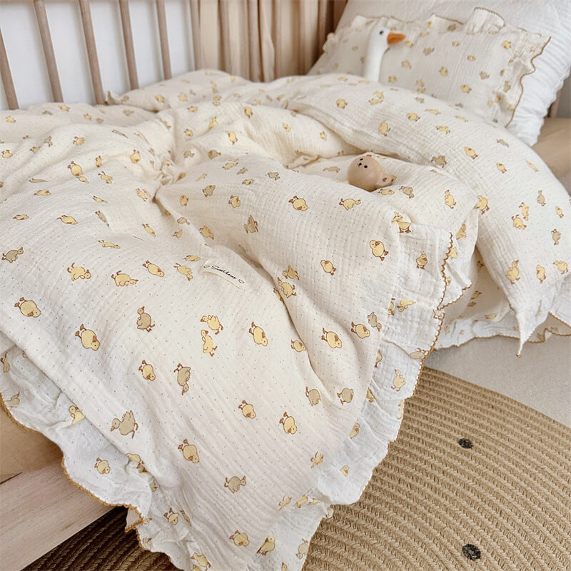 Duckling print cotton muslin bedding set with ruffled pillow in a crib