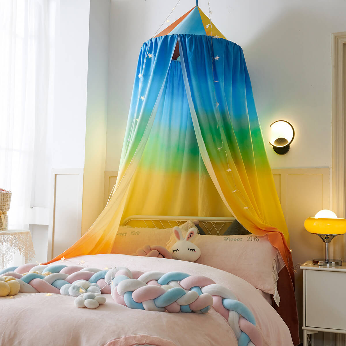 Round colorful bed canopy acting as a cozy playhouse over a crib.
