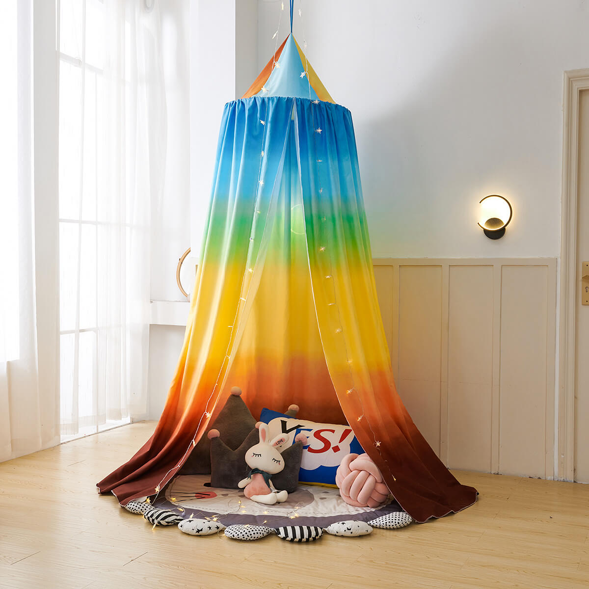 Colorful nursery tent featuring a rainbow pattern, set up as a play space on the floor.