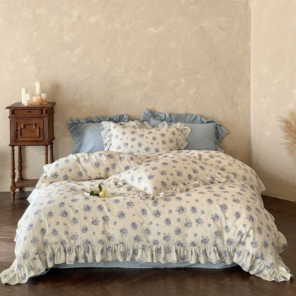 A complete look at the cotton blue floral bedding set in a French country-style bedroom, showing the duvet cover, flat sheet, and pillows on a wooden bed frame.