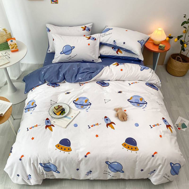 A cotton space duvet cover on a bed. The bedding has colorful cartoon illustrations of planets and rockets on a white background, with a solid navy blue reverse side visible.