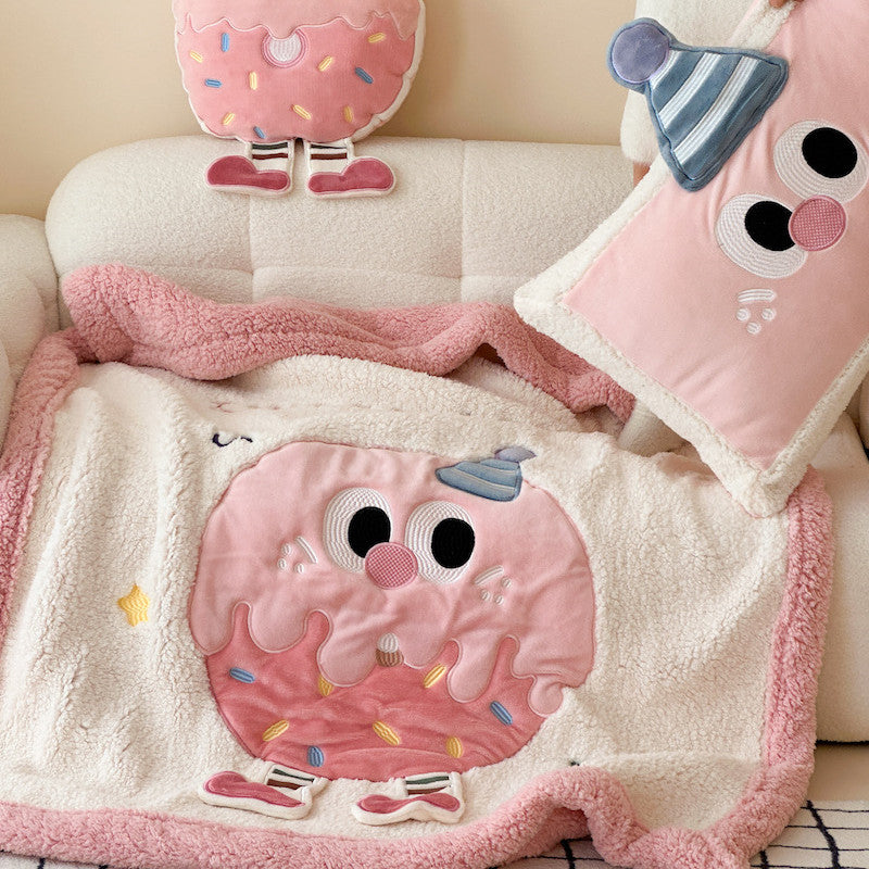 Pink plush sherpa throw blanket with donut design on a sofa, with matching pillows.