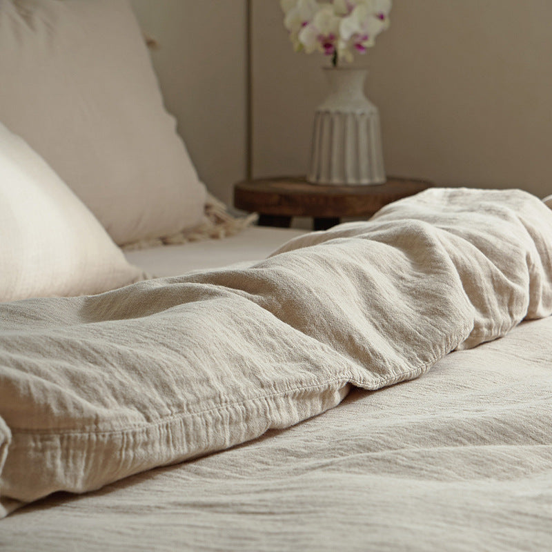 A detailed view of a khaki cotton gauze duvet cover, showing the soft folds of the fabric and the subtle fringe along the edge.